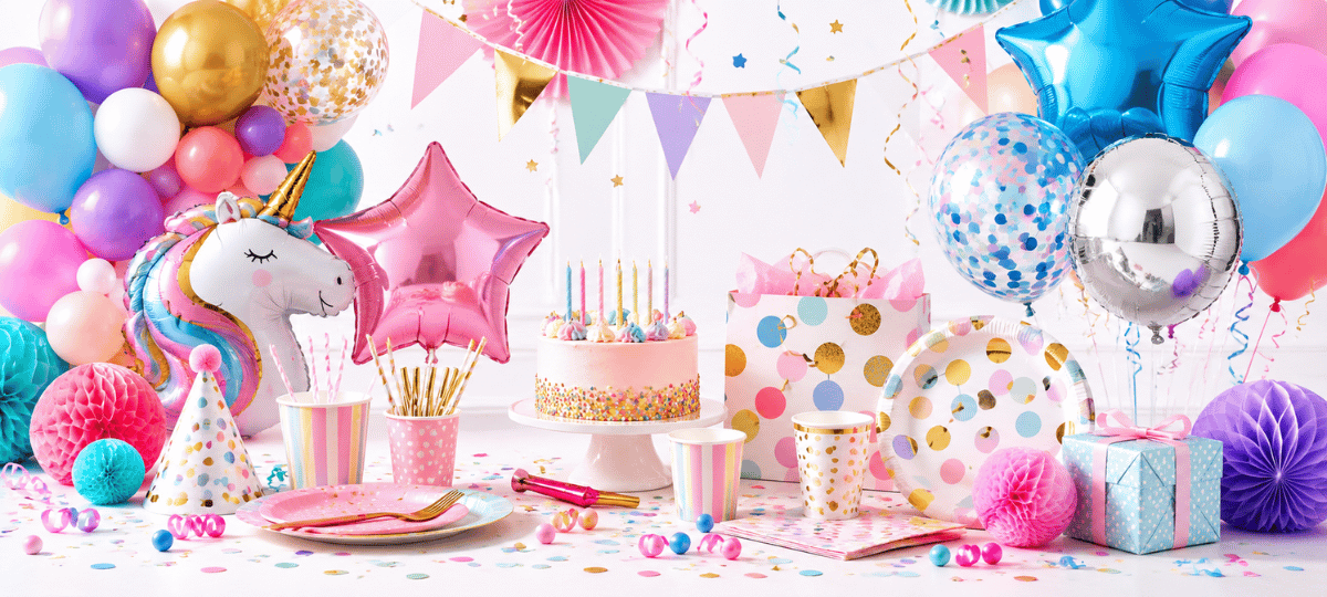 Bunt dekoriertes Partyset mit Ballons, Geburtstagstorte, Papptellern, Bechern, Geschenken und Partydekoration für verschiedene Feierlichkeiten.